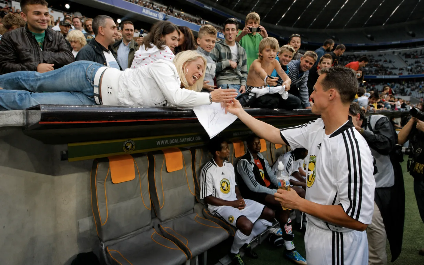Goal4Africa player greeting a supporter beside the pitch at the Allianz Arena.