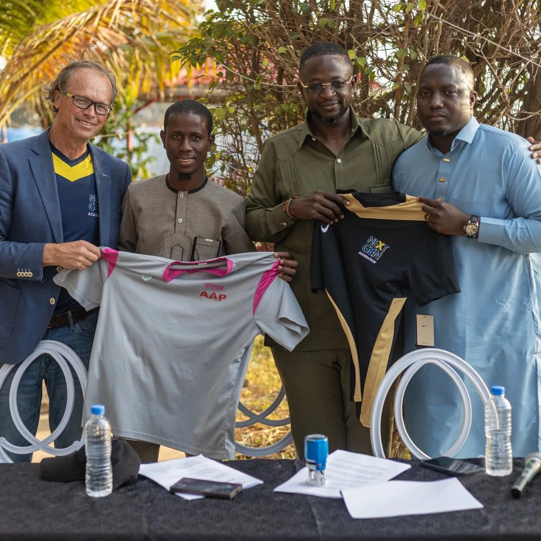 NEXTGEN Foundation and SOAR Academy representatives holding football shirts after the partnership presentation.